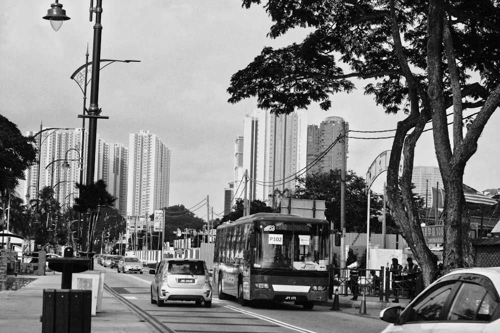 grayscale photography of car and bus on road