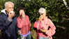A joyful group tasting cider outdoors among apple trees.