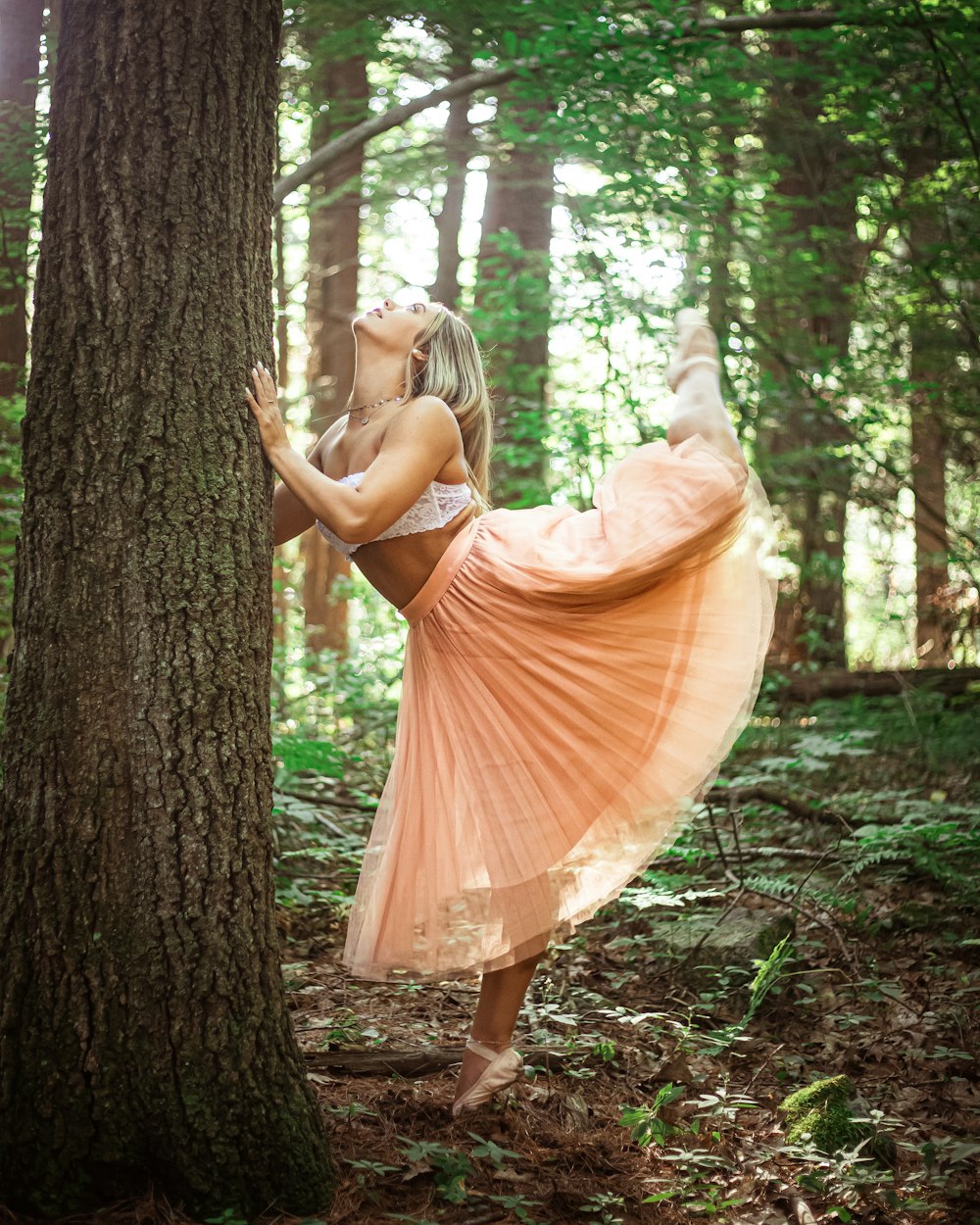 woman in white crop top and pink maxi skirt stretching outdoors