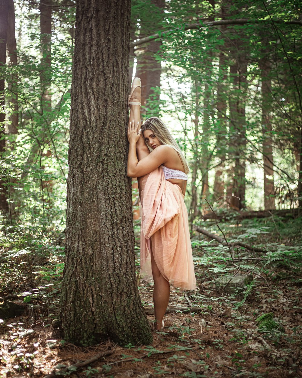 woman in white crop top and pink maxi skirt stretching outdoors