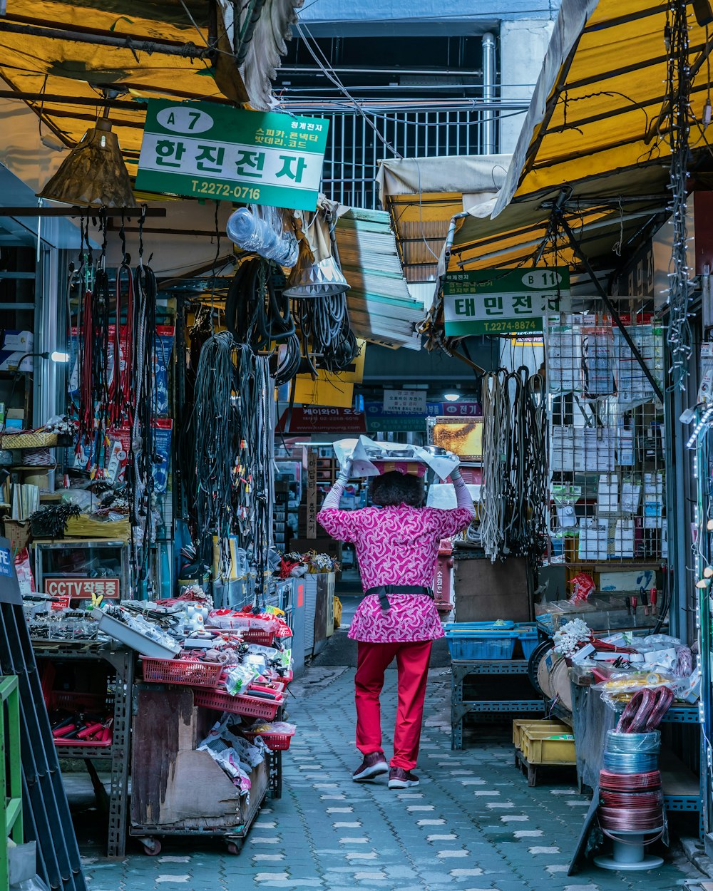 person in pink top walking beside stores