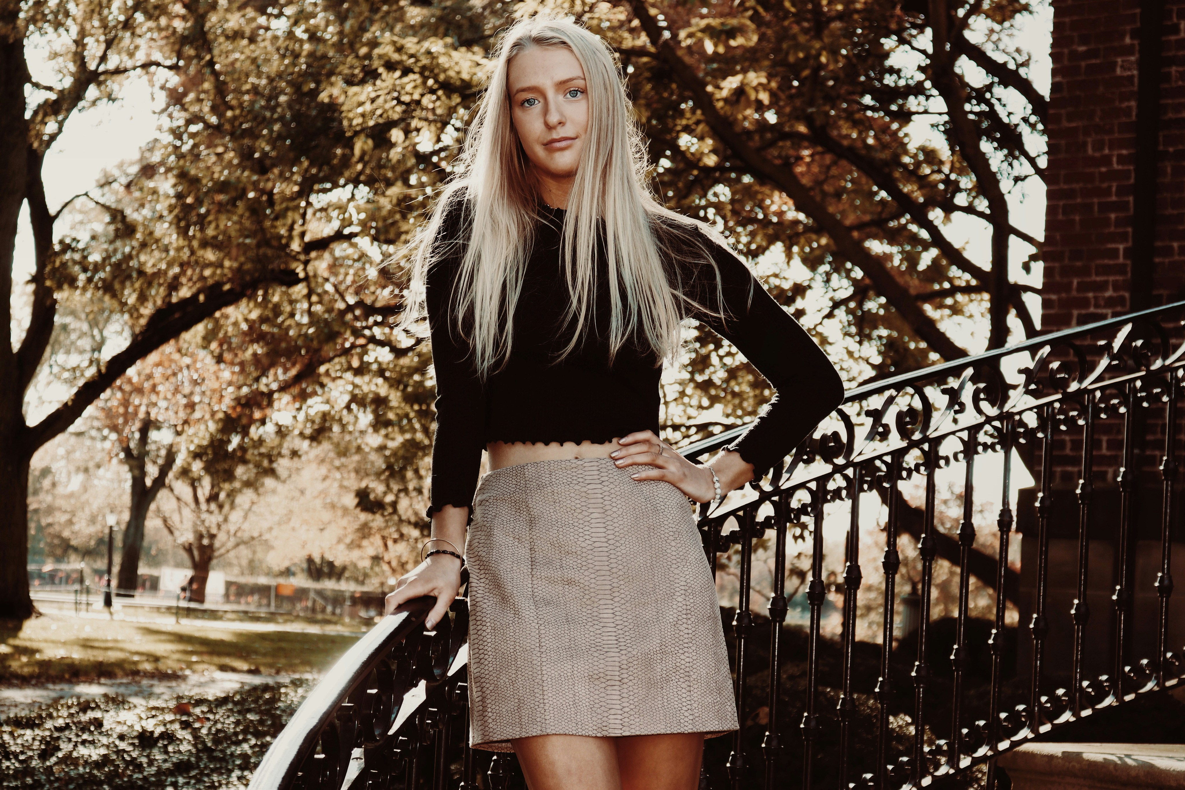 woman in black long-sleeved top and gray skirt leaning on black stair handrail