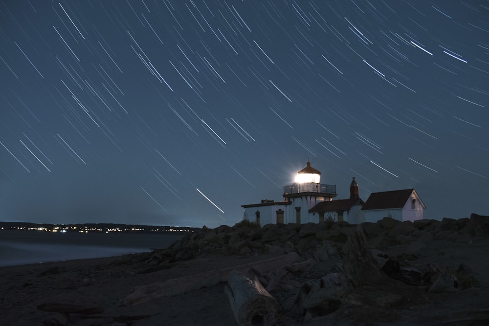 white and black lighthouse by the sea during nighttime