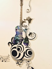 A colorful, whimsical illustration of a guitar surrounded by musical notes and paint splashes.