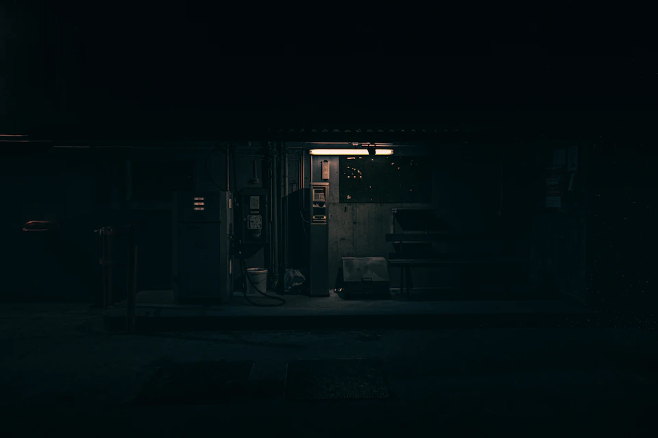 Dimly lit room with single light source casting long shadows on concrete floor