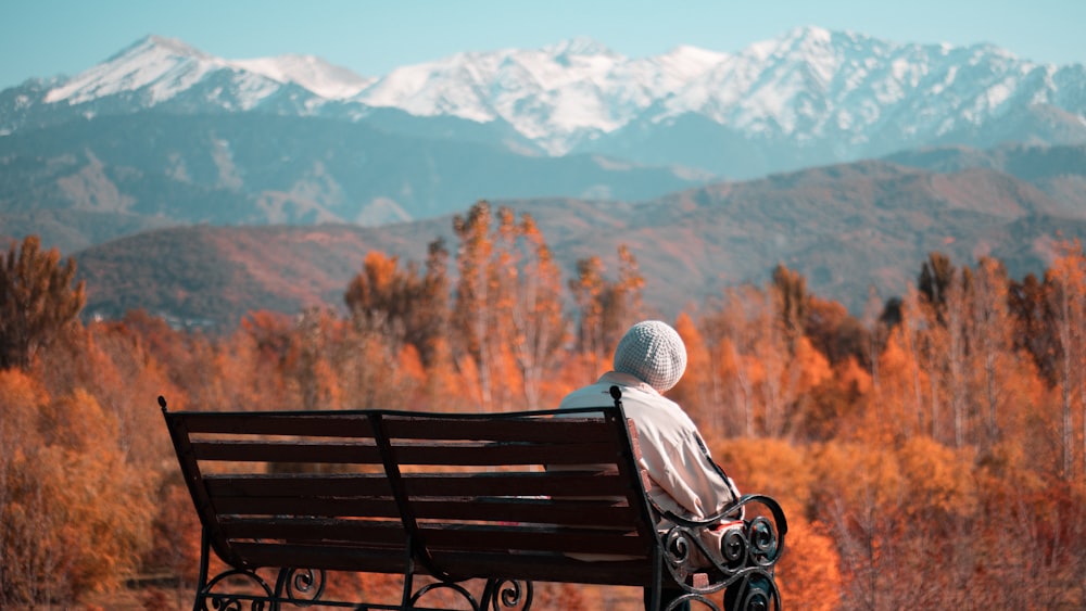 woman sitting on a bench fronting a snowy mountain