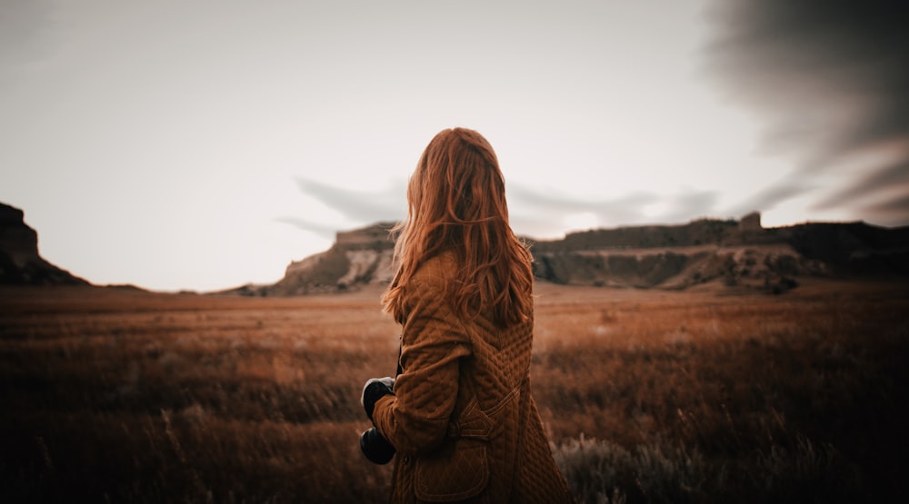 woman standing in an open field facing to the back