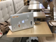 A person decorating a laptop with multiple stickers in a cozy setting.