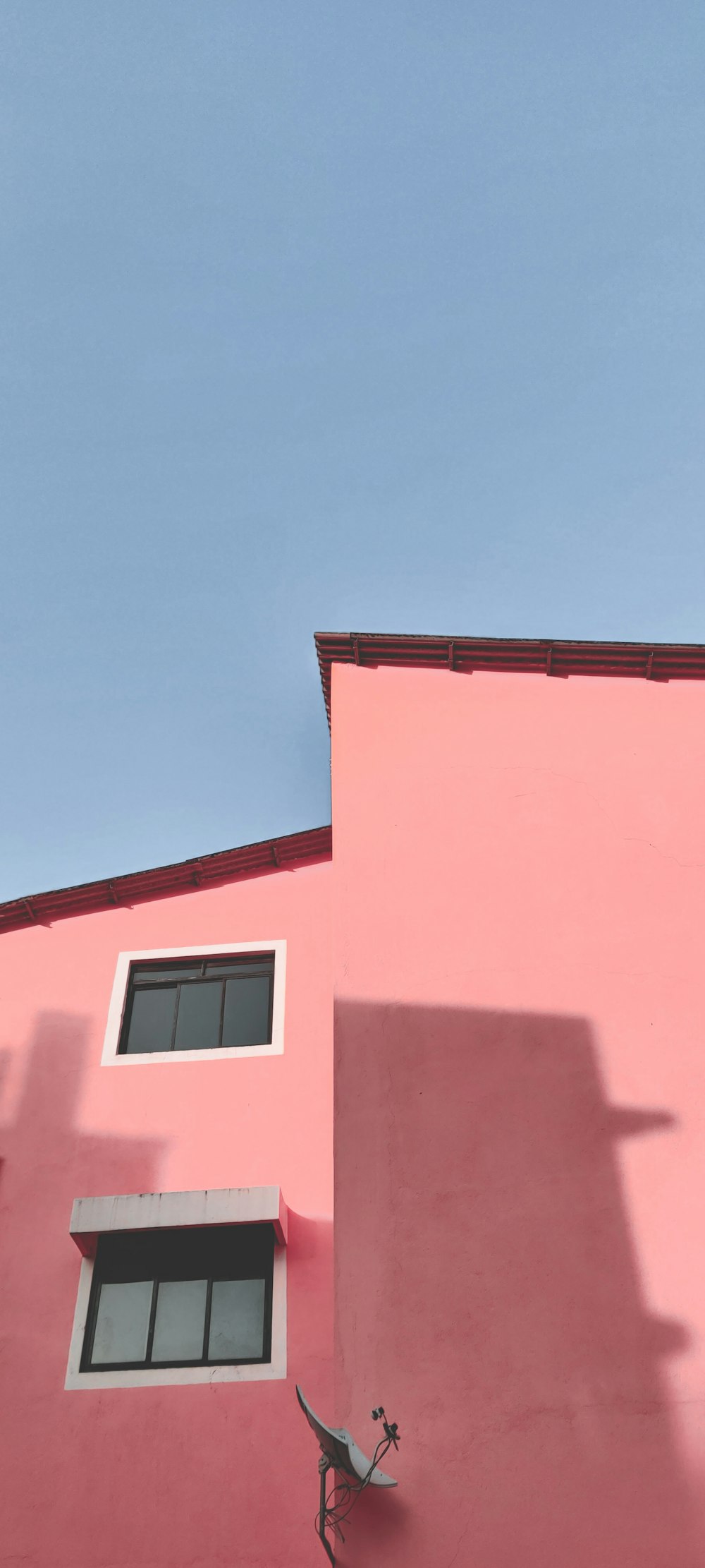 pink concrete multi-storey building under a calm blue sky