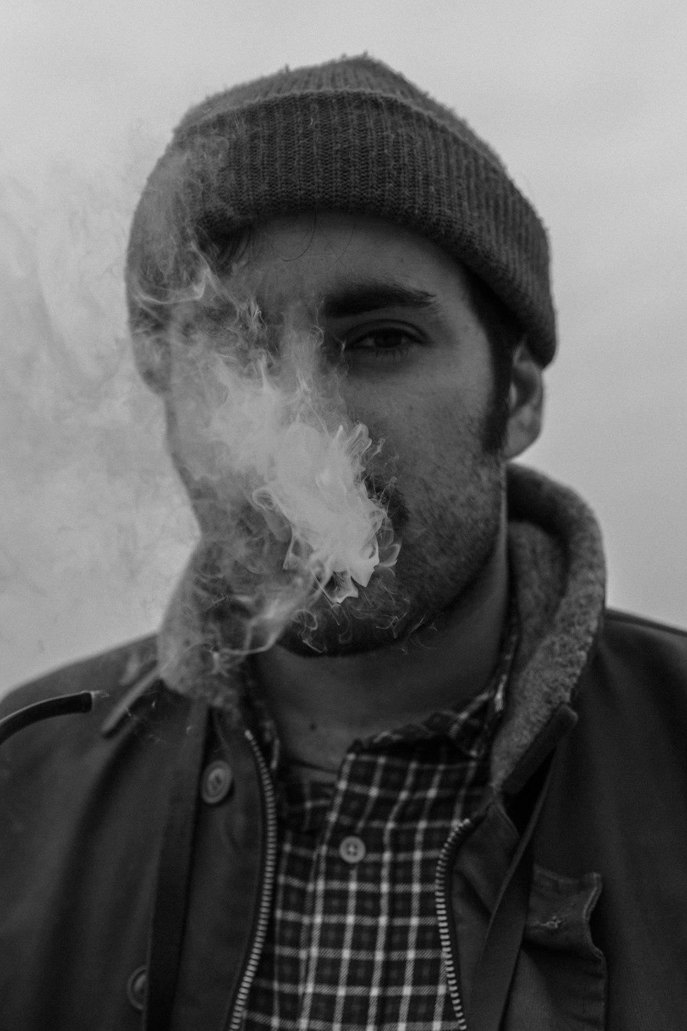 Photo en niveaux de gris d’un homme fumant