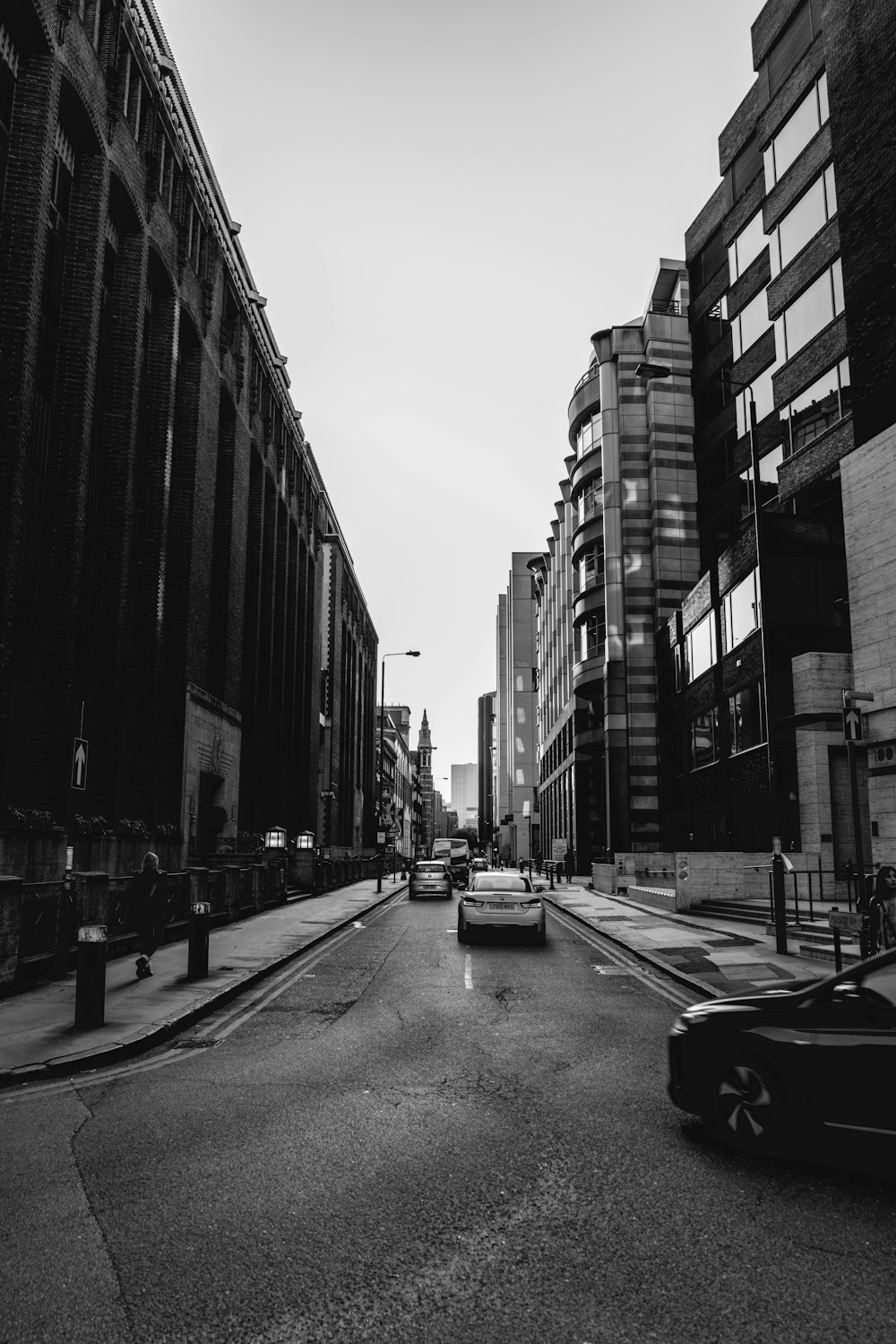 grayscale photo of vehicles on street between buildings