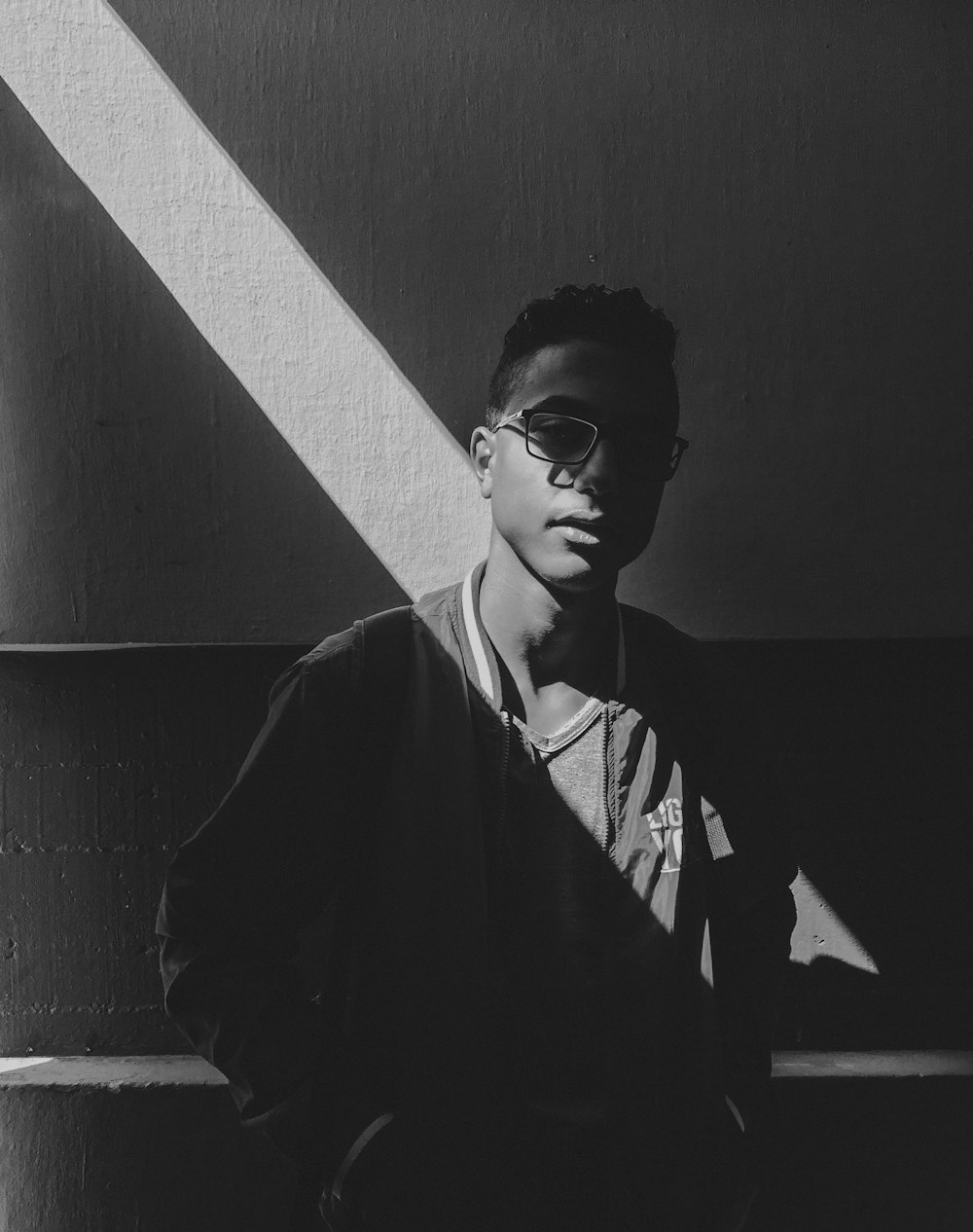 grayscale photo of light through man in jacket