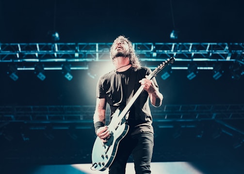 Close-up of a guitarist passionately playing on stage with red and black lighting.