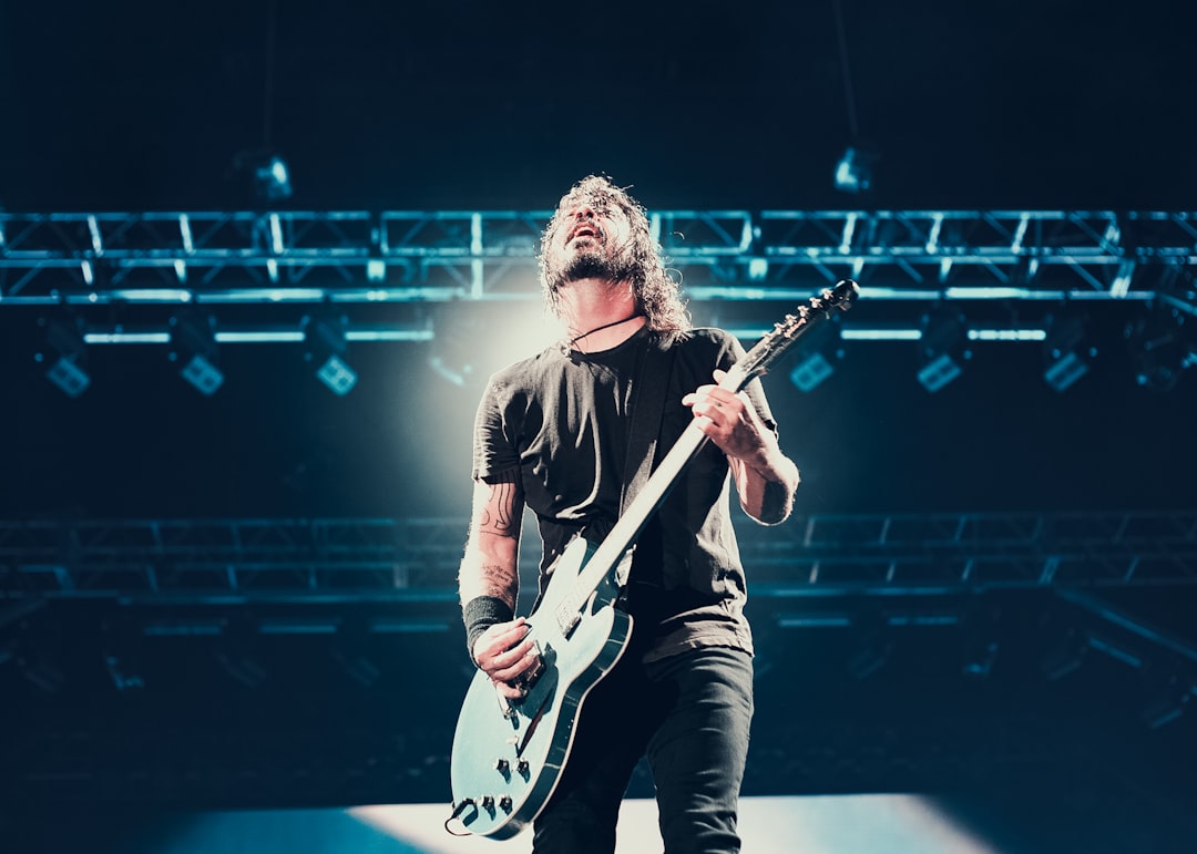 man playing guitar under stage light struss