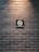 A dark brick wall features a prominently placed 'No Smoking' sign. The sign is centered and displays a cigarette with a red circle and slash, conveying the prohibition.