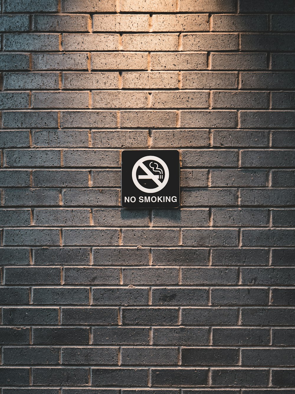letrero de prohibido fumar en la pared de ladrillo