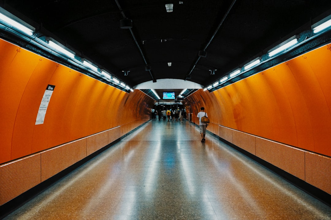 man walking beside orange wall