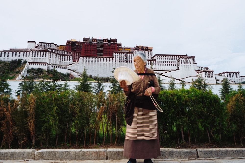 woman holding folding hand fan outside Potala Palace