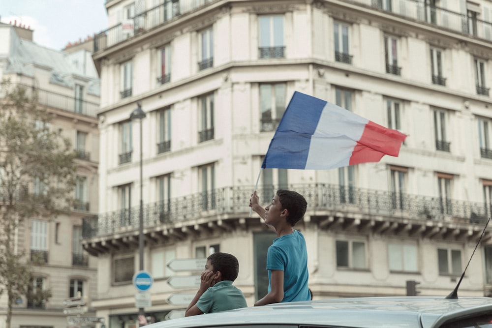 파란 티셔츠를 입은 남자가 프랑스 국기를 들고 있다