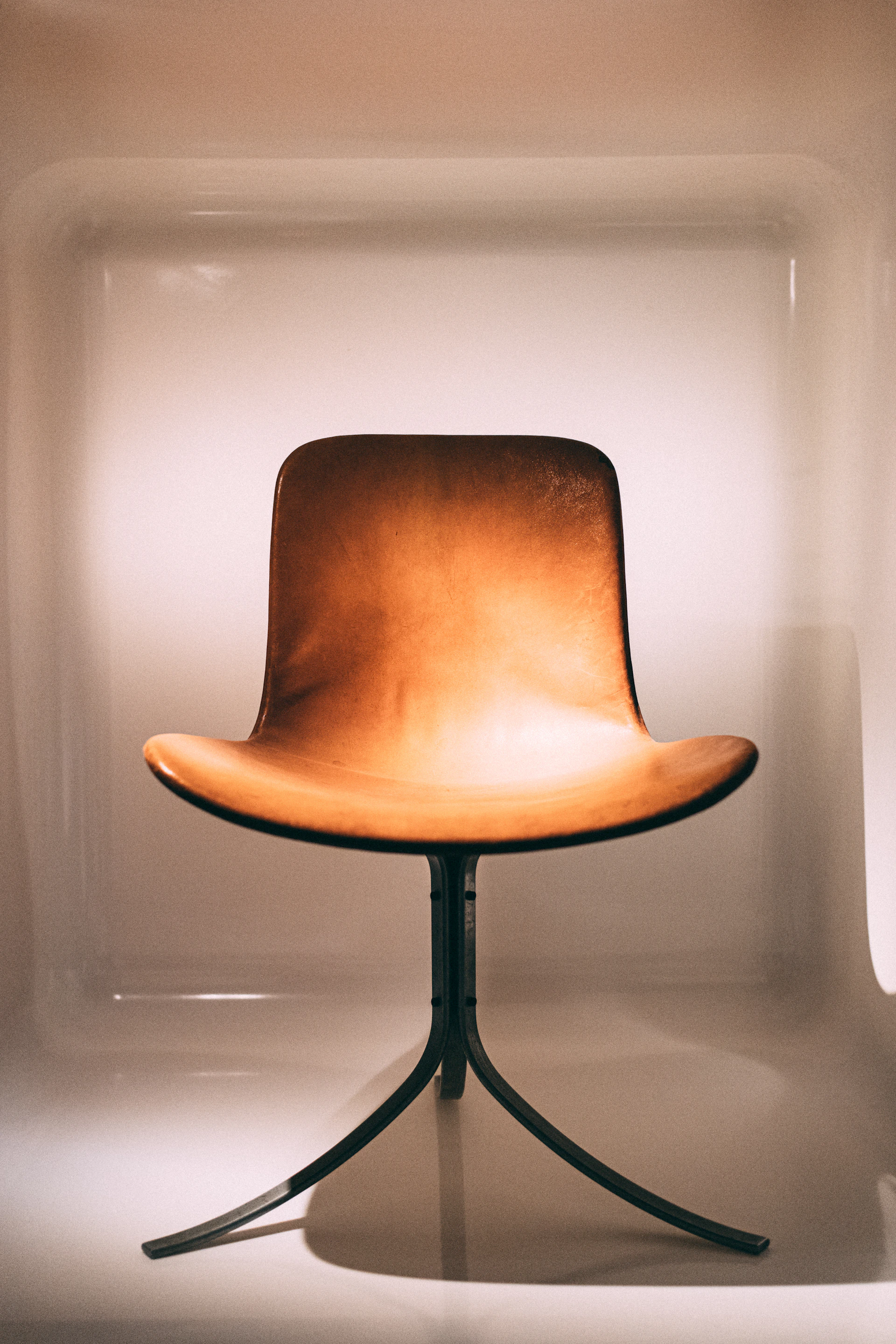 A beautifully crafted wooden chair with smooth curves and a polished finish, set against a warm beige background.