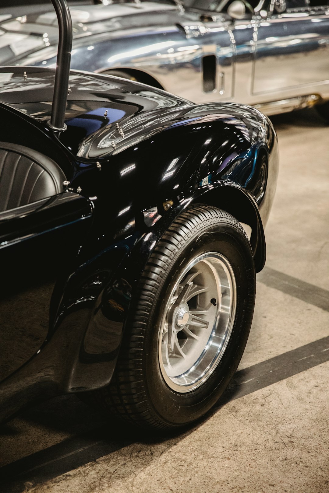 vintage black convertible coupe inside room beside gray vehicle