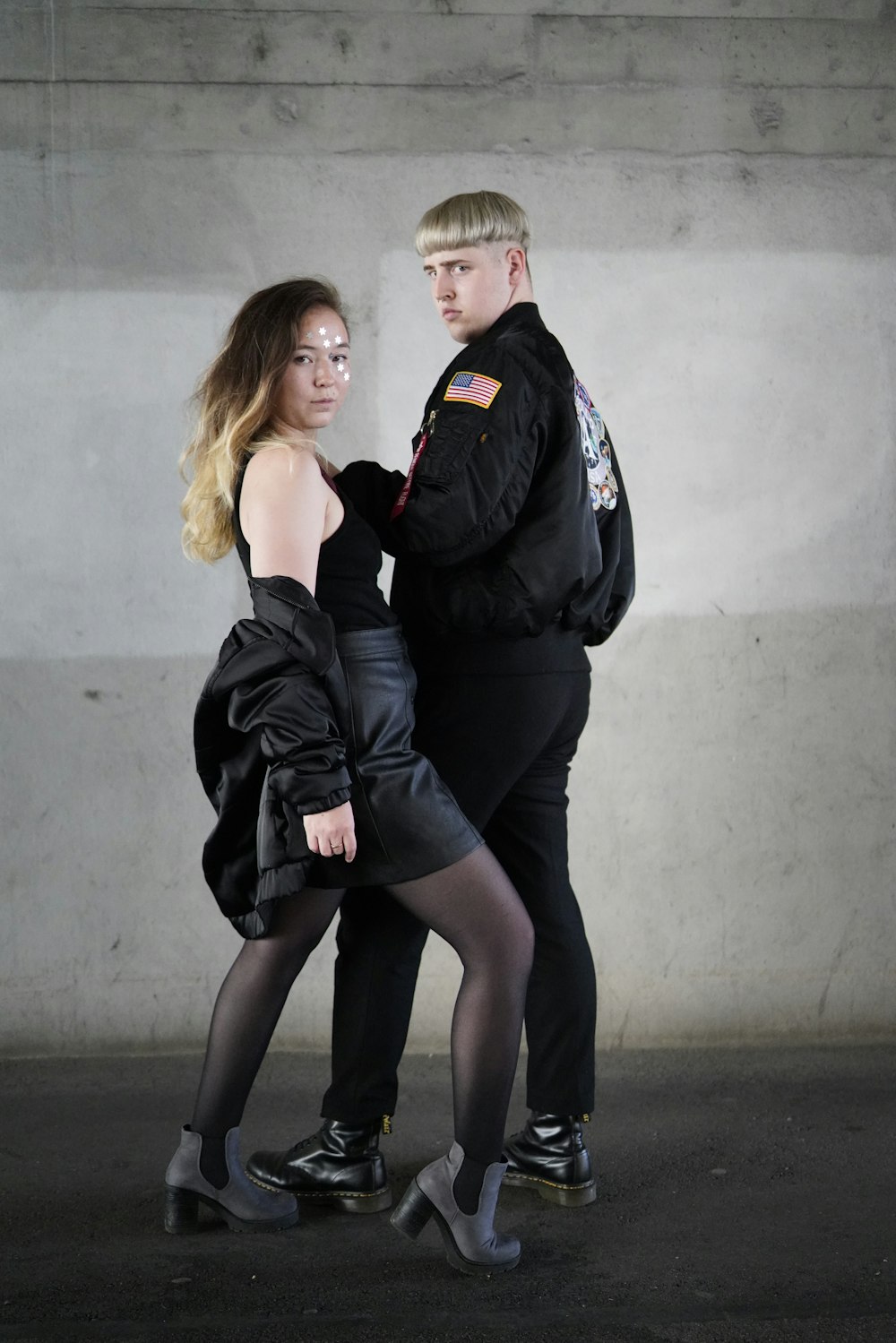 man wearing black jacket and black pants and woman wearing black blouse with black leather skirt