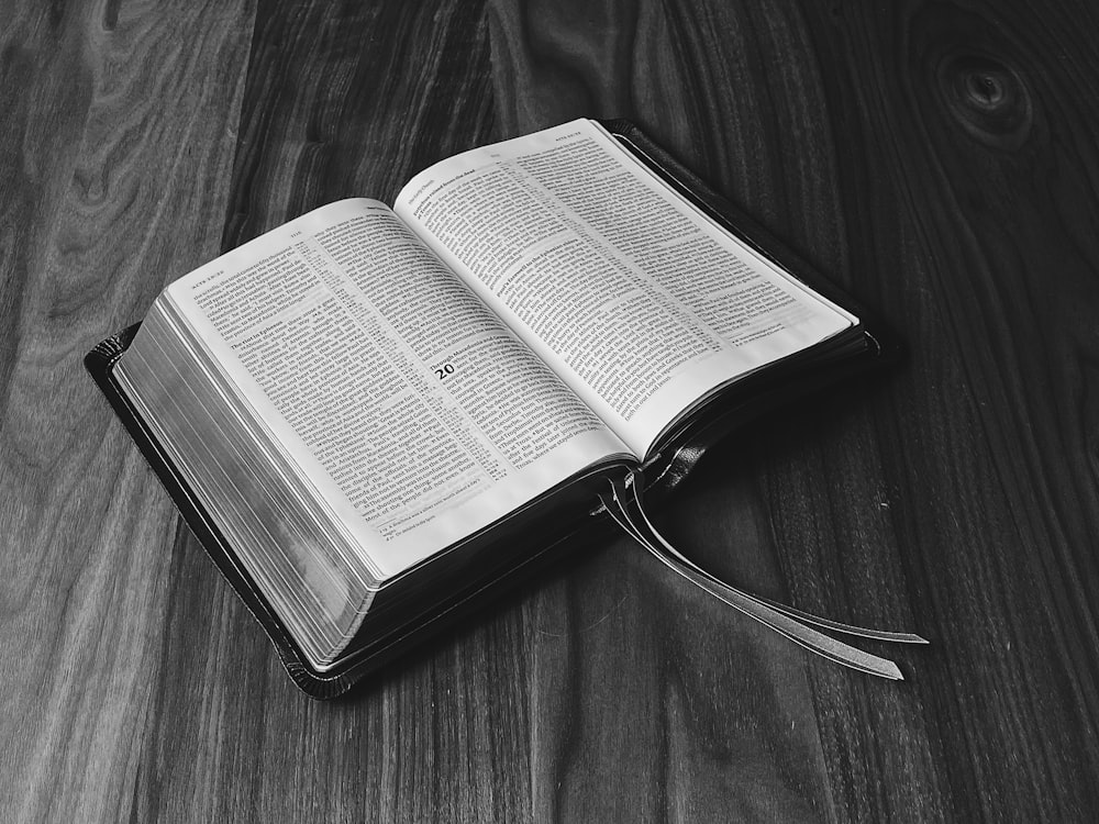 grayscale photo of book on wooden surface