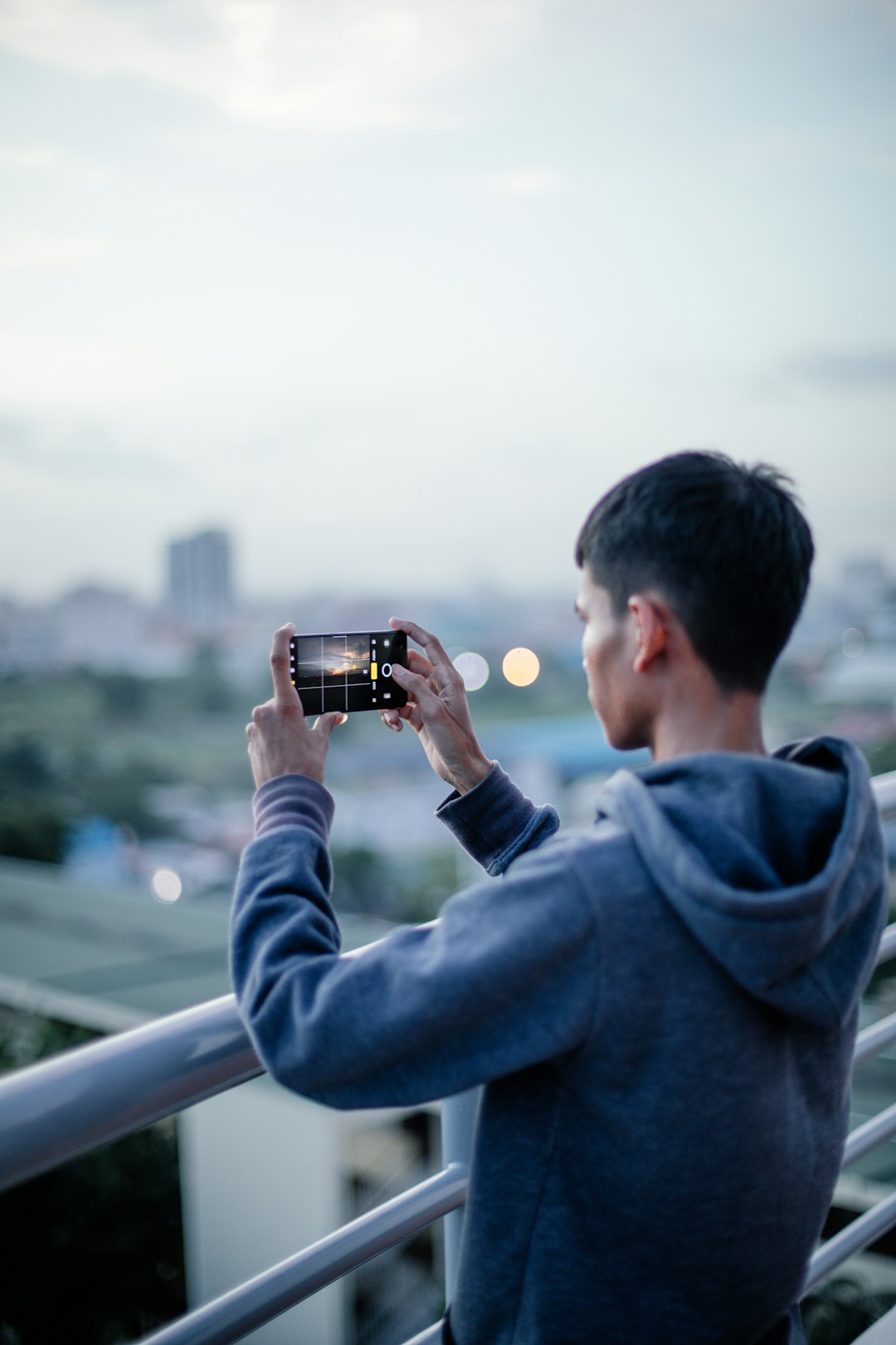 man holding smartphone with gray pullover hoodie