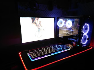 two black flat screen computer monitors and gaming keyboard
