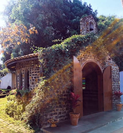 A small charming chapel surrounded by lush greenery and flowers.