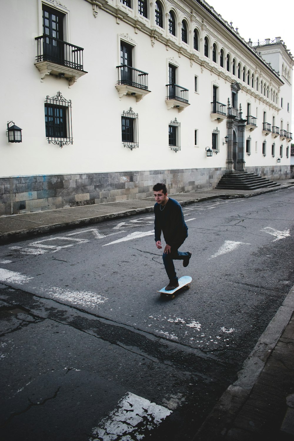 man wearing black long-sleeved shirt and black jeans riding skateboard