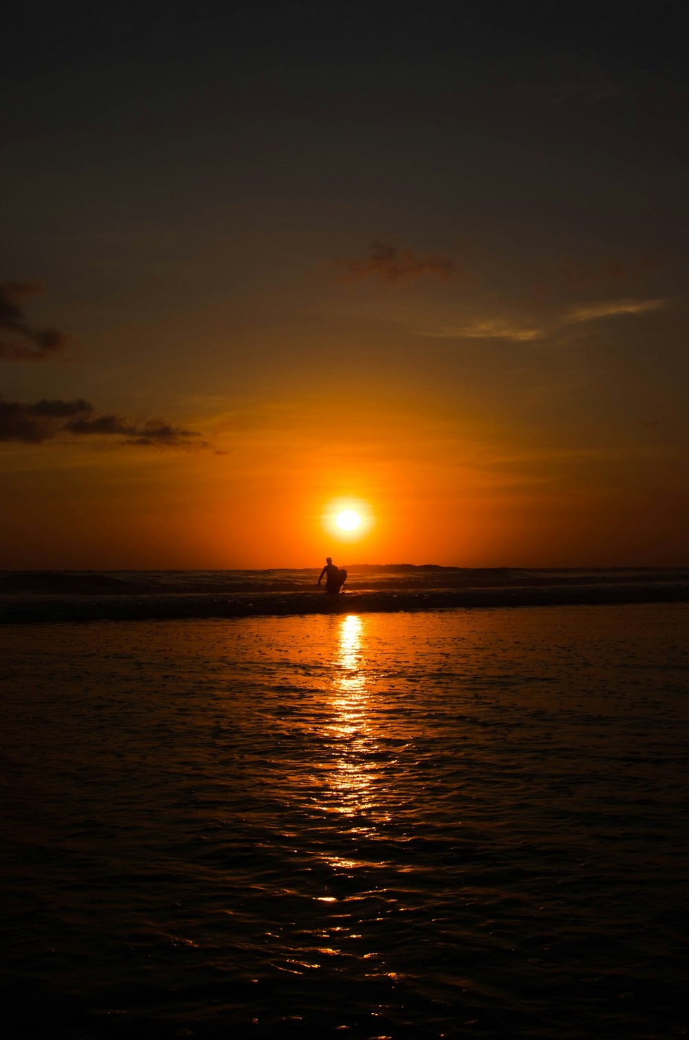 silhouette of man walking on seashore during sunset