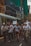 A group of people are marching in a city street, holding signs and banners with environmental messages. Buildings and a tram are visible in the background, suggesting an urban setting. Some individuals are using a megaphone to amplify their voices, indicating a protest or demonstration.