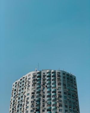 A friendly technician inspecting a residential apartment exterior on the Gold Coast under a bright blue sky.