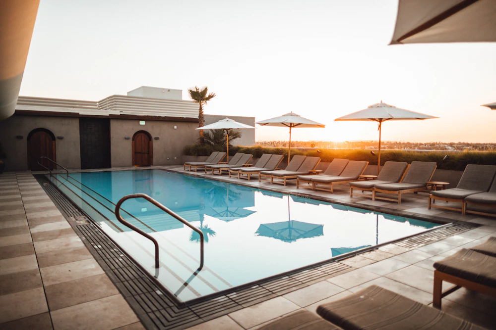 Sunset over a decorative paved pool deck with loungers