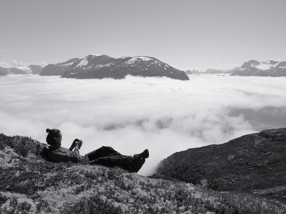 man lying on mountain near clouds during day