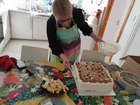 A cozy kitchen scene with a baker decorating a colorful cake.