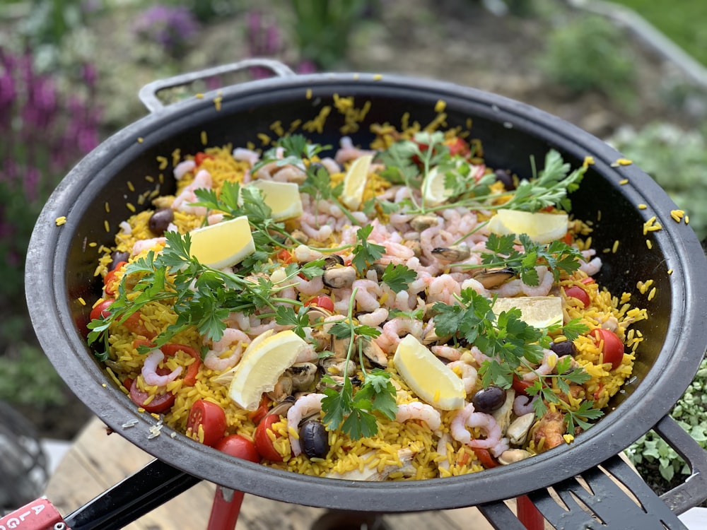 a pan filled with rice and vegetables on top of a grill