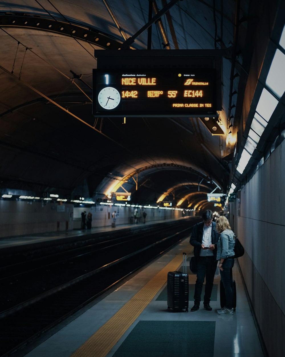 two person standing beside train rails