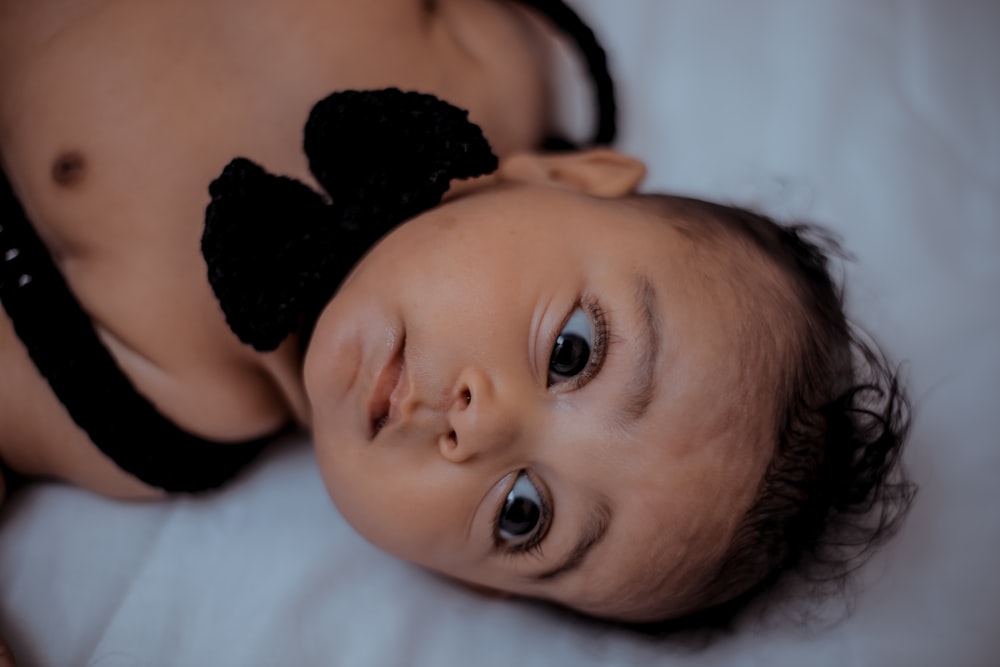 baby lying on bed wearing black bowtie