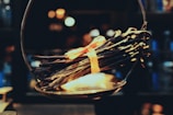A bundle of dried vanilla beans tied together with an orange ribbon rests on a vintage scale. The background is softly blurred, creating a warm and cozy ambiance with bokeh lights.