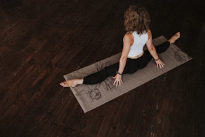 A yogi stretching gracefully on a soft beige mat, wearing sleek, form-fitting yoga apparel