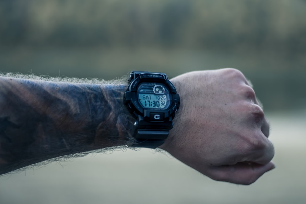 person wearing black round digital watch