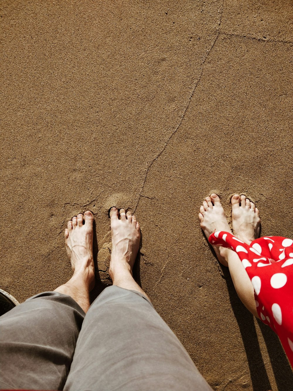 man and woman standing on sand during day