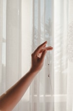 person holding window curtain during daytime