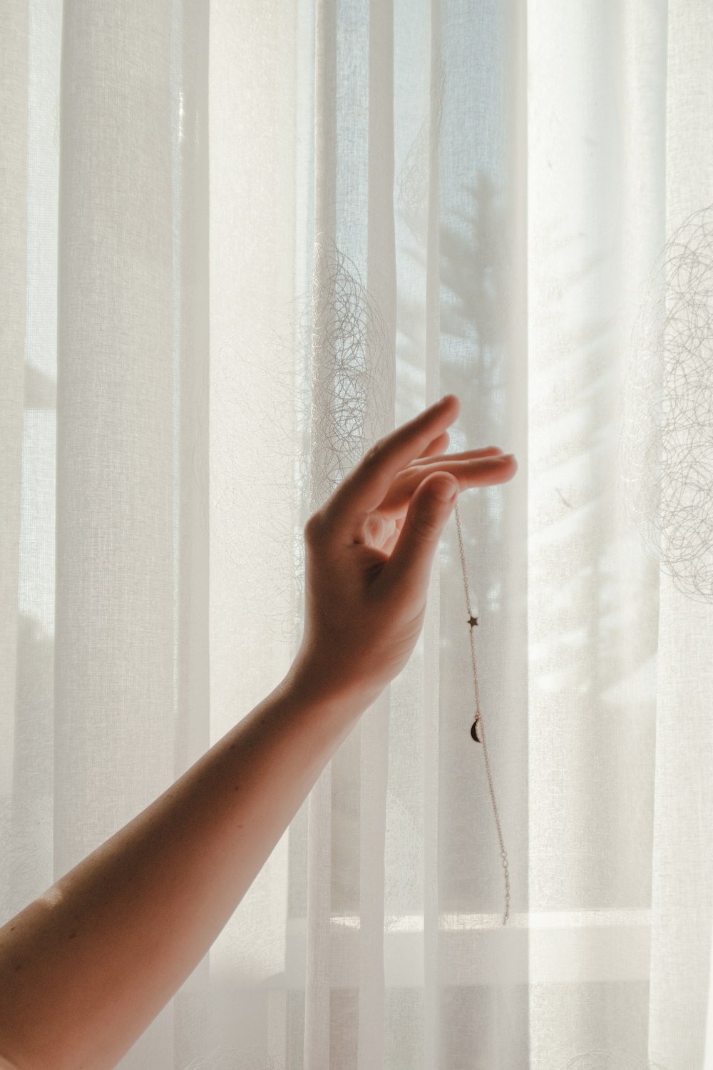 person holding window curtain during daytime