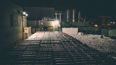A sleek, dark-toned image of oil barrels stacked in a high-tech storage facility at dusk.