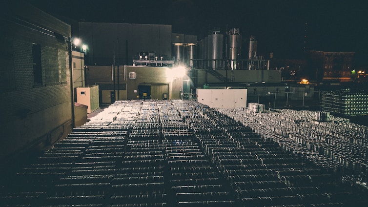 Industrial warehouse with fuel tanks and glowing orange accents under deep blue lighting.