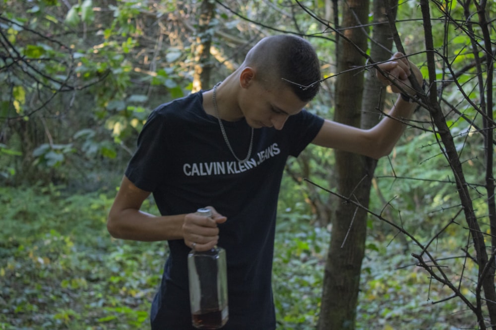 man wearing black and white shirt holding tree branch