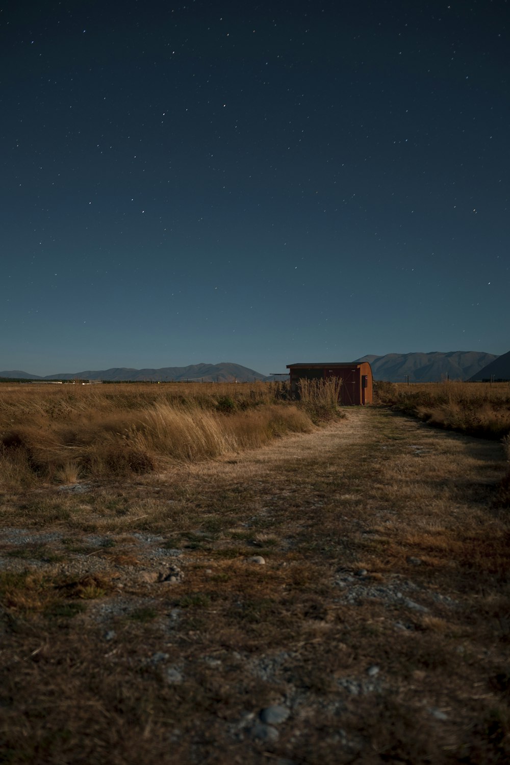 red house surrounded by brown grass field under blue sky